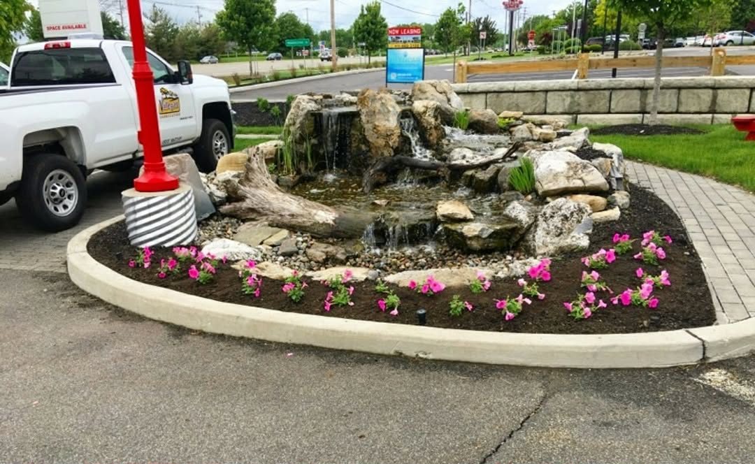 Landscaped commercial entrance with stone fountain and flower beds